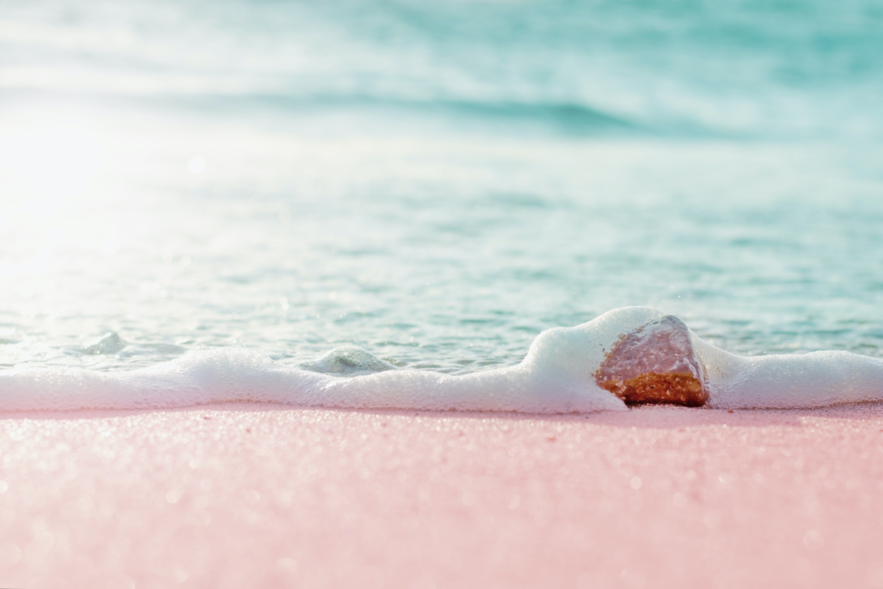 Summer pastel colored background - sandy beach and sea water over small stone